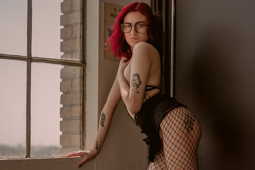 She leans against the windowsill exposing her ass and tattoos