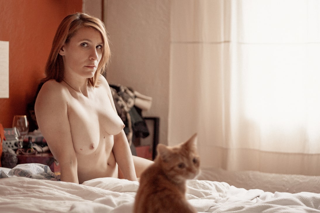 Portrait of naked woman on her bed with her cat