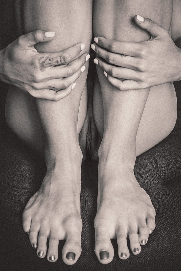 Close-up photo of young woman's feet, hands, and vagina