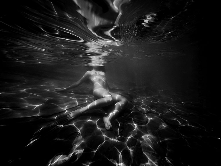 Underwater photo of nude woman reclining on lakebed