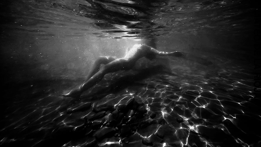 Fine art photo of nude woman floating below the water surface
