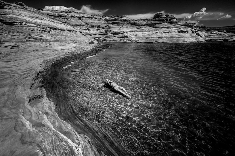 Landscape of nude woman swimming on her back next to the rocks in Lake Mead