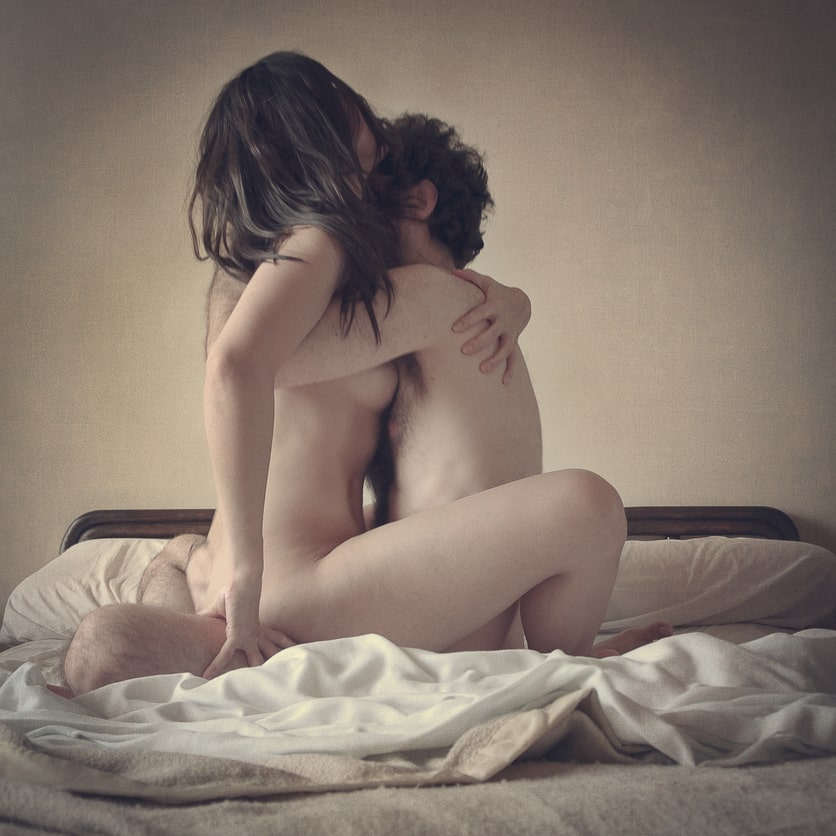 young couple embracing and kissing while they have sex in the lotus sex position